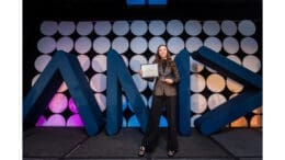 Valerie Ruiz onstage holding up an award certificate