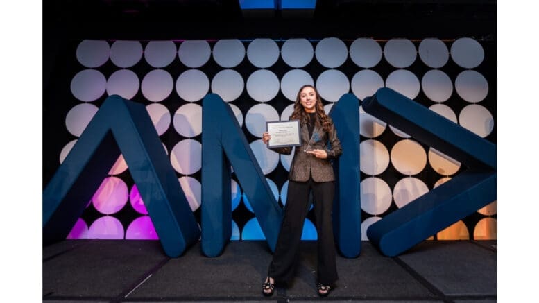 Valerie Ruiz onstage holding up an award certificate