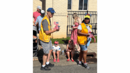 Man and woman handing out flags on a parade route