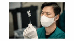 A masked medical professional drawing vaccine into a syringe