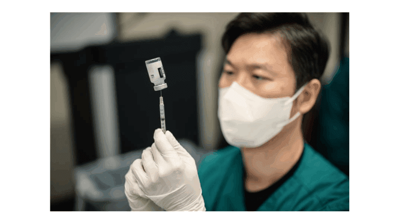A masked medical professional drawing vaccine into a syringe