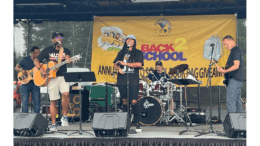 A band with electric instruments and drums performs onstage