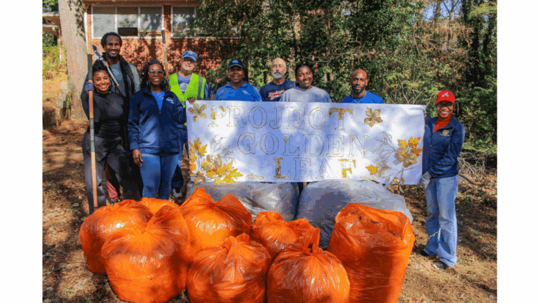 A group photo of participants in the Golden Leaf cleanup program holding a banner and standing in front of a line of pumpkins