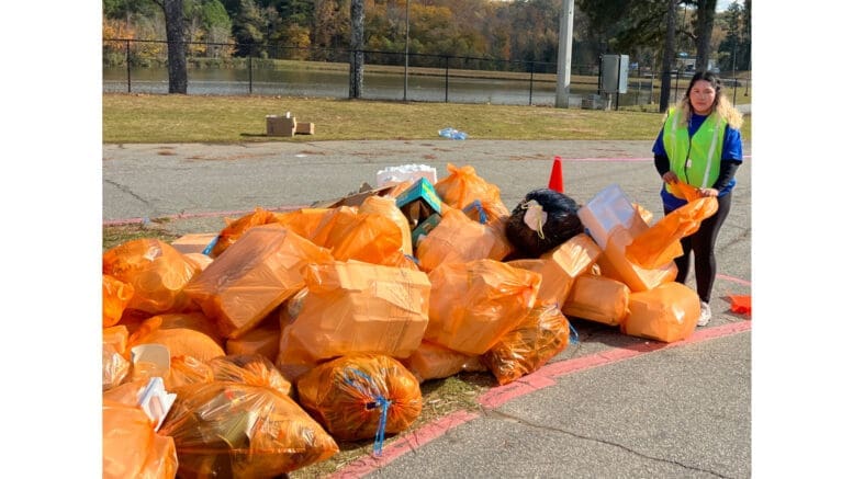 Bags of recycle plastic at Keep Cobb Beautiful event, with volunteer standing by