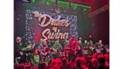 The band Dukes of Swing sit, with instruments, onstage