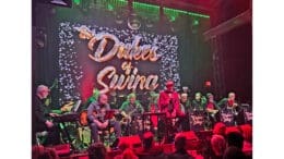 The band Dukes of Swing sit, with instruments, onstage