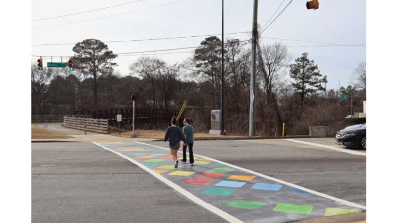 Two people walk across the decorative crosswalk in the Town Center area along Noonday Creek Trail