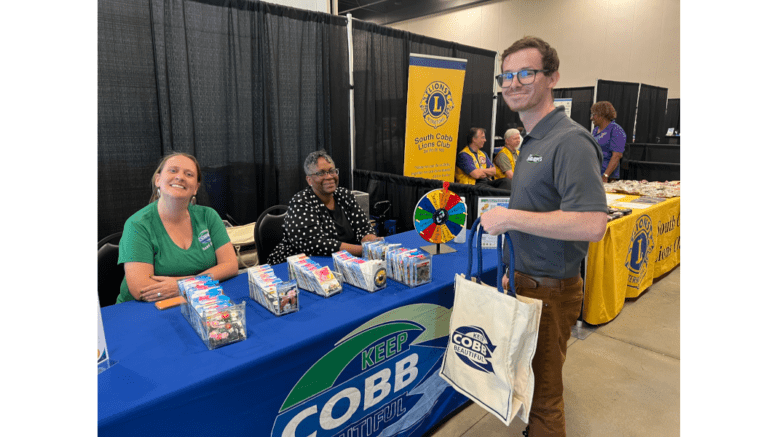 Keep Cobb Beautiful table at the Cobb Sustainability Expo with two women at the table and a man with a KCB bag at the front