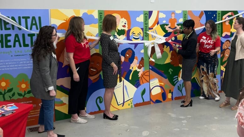 Commissioner Monique Sheffield cuts the ribbon on the Paint Love mural