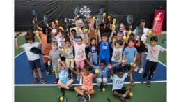 A group of children and adults on a newly opened pickleball court