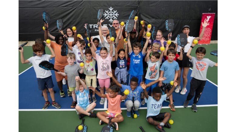 A group of children and adults on a newly opened pickleball court