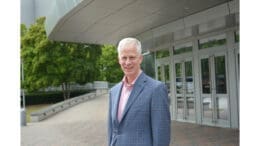 Tom Rowland in coat and dress shirt without tie stands in front of the Cobb Energy Performing Arts Centre where he has been appointed managing director