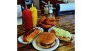 Photo of a hot dog, hamburger and onion rings with condiments